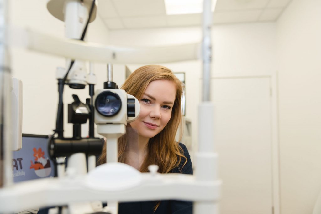 Optometrist Gemma Hill, standing behind sight test equipment